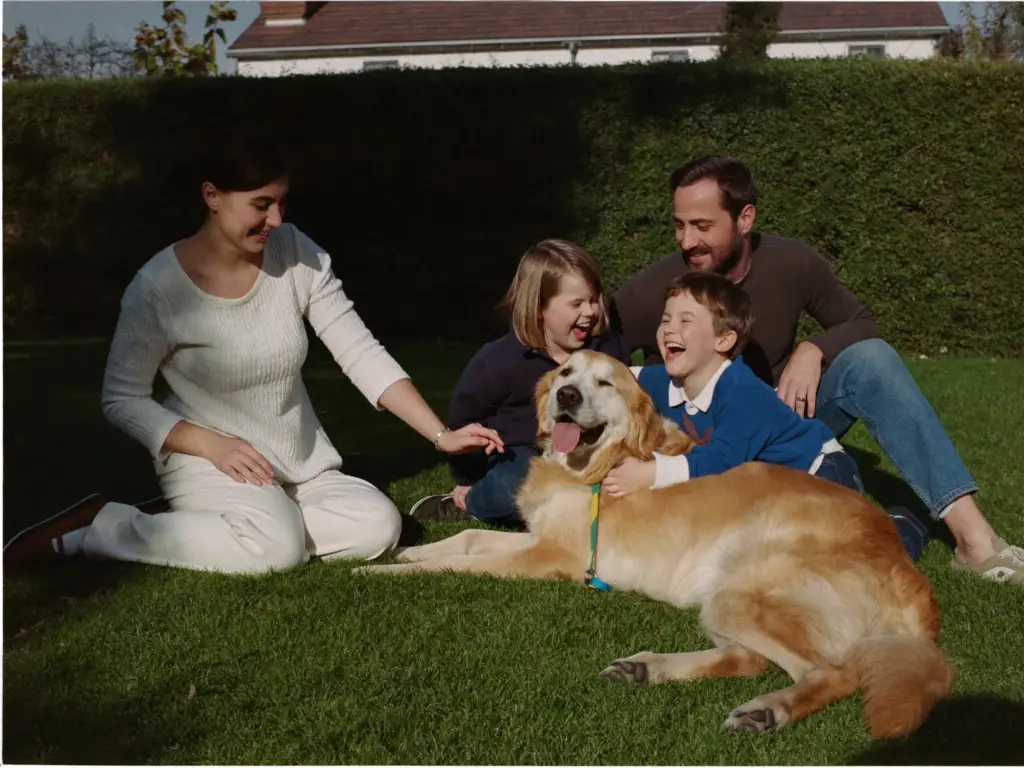 Sanne, Rick en hun twee kinderen in de tuin met hun Golden Retriever Moos
